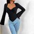 Woman wearing black sweetheart neckline top with flared sleeves, paired with light jeans and layered gold necklaces
