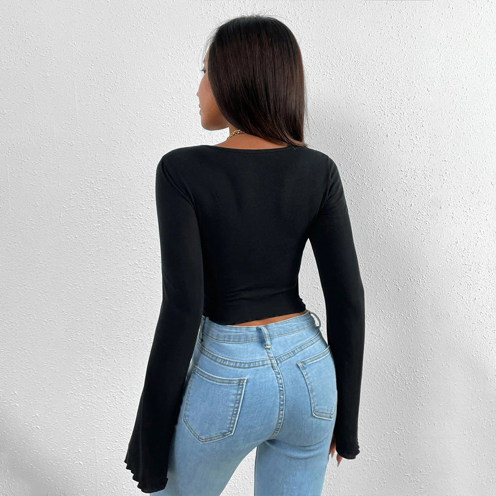 Back view of black long-sleeve crop top with flared sleeves and high-waisted light wash jeans
