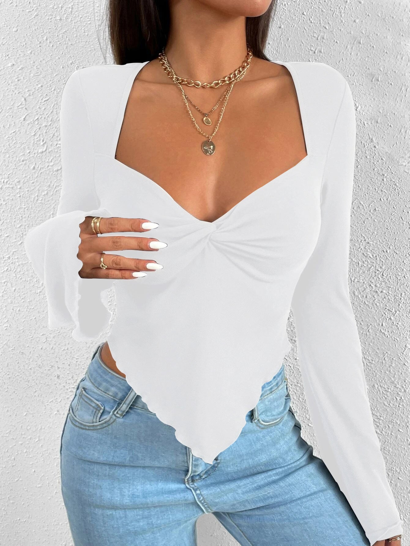 White twisted front bodysuit with sweetheart neckline and long sleeves, paired with light denim jeans