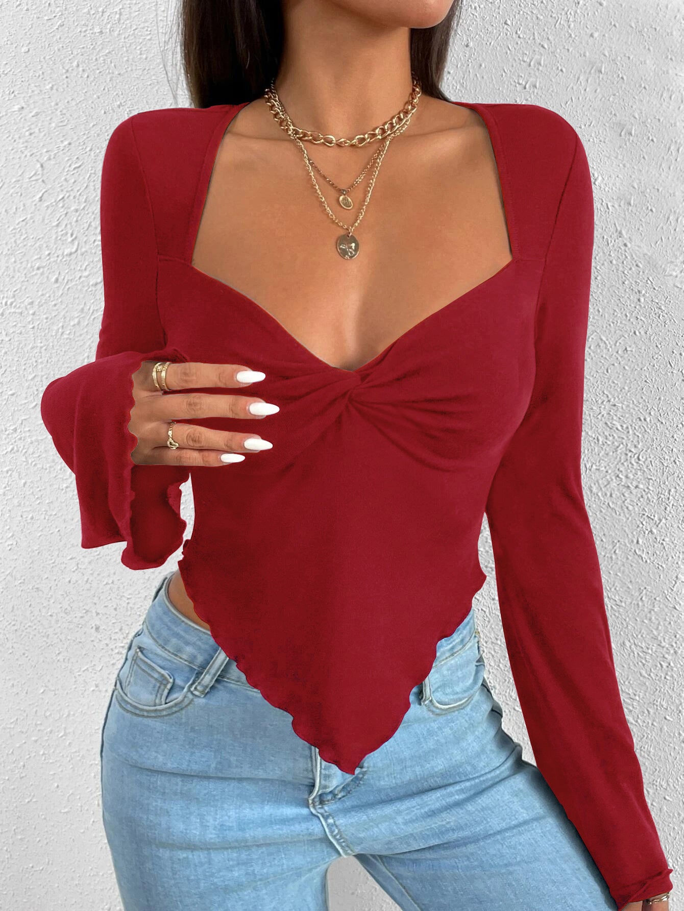 Burgundy long-sleeve bodysuit with sweetheart neckline and front twist detail, worn with light jeans