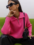 A woman in a pink ribbed zip-collar sweater and black sunglasses is sitting on a green couch, carrying a black handbag