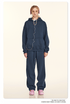 Model in navy hoodie and sweatpants set with pink headphones and matching sneakers on beige backdrop