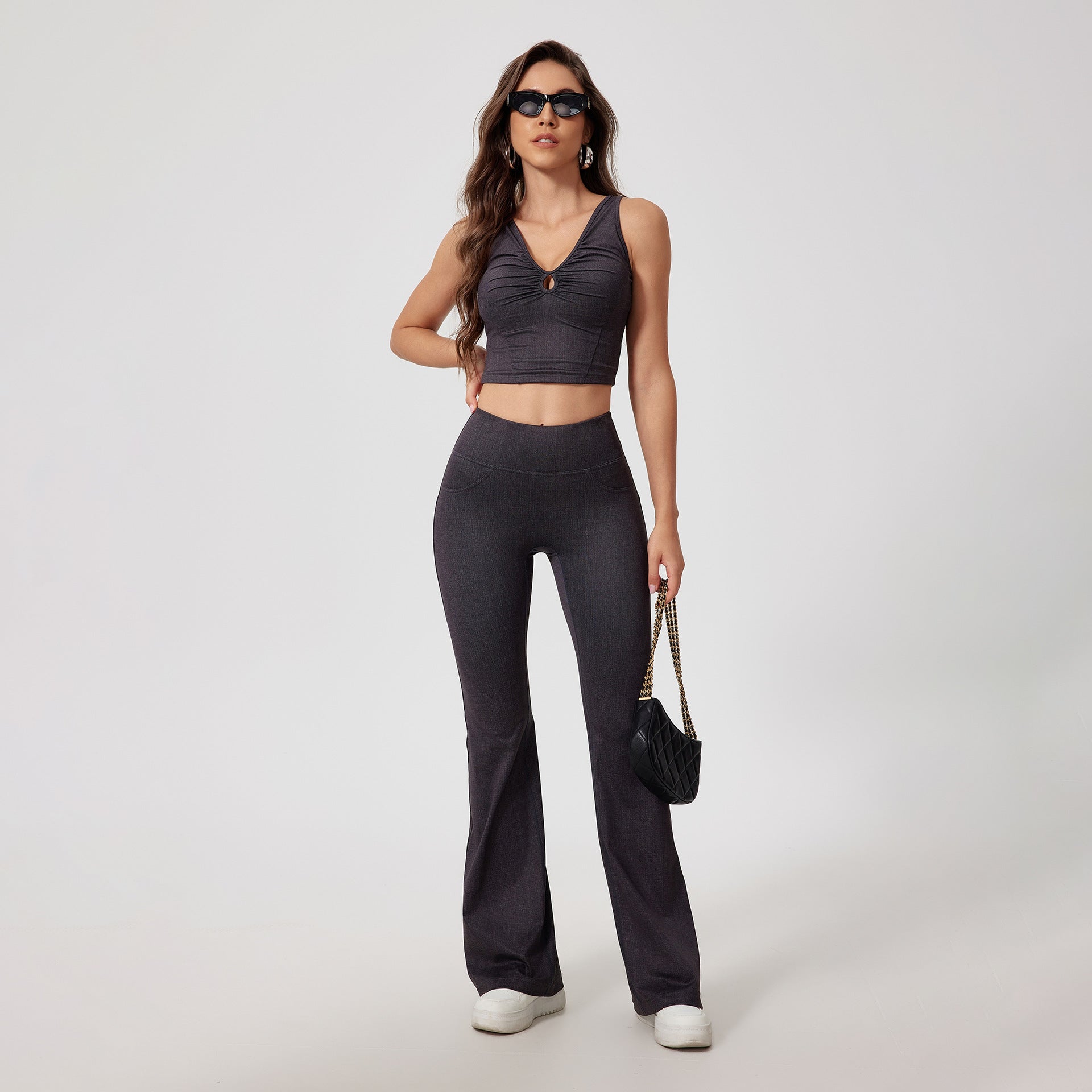 Full-length charcoal denim workout set with cropped tank and flared pants, styled with sunglasses and black shoulder bag