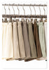 Metal clothing hangers with clips holding various neutral-colored shorts with drawstring waistbands displayed on a rack