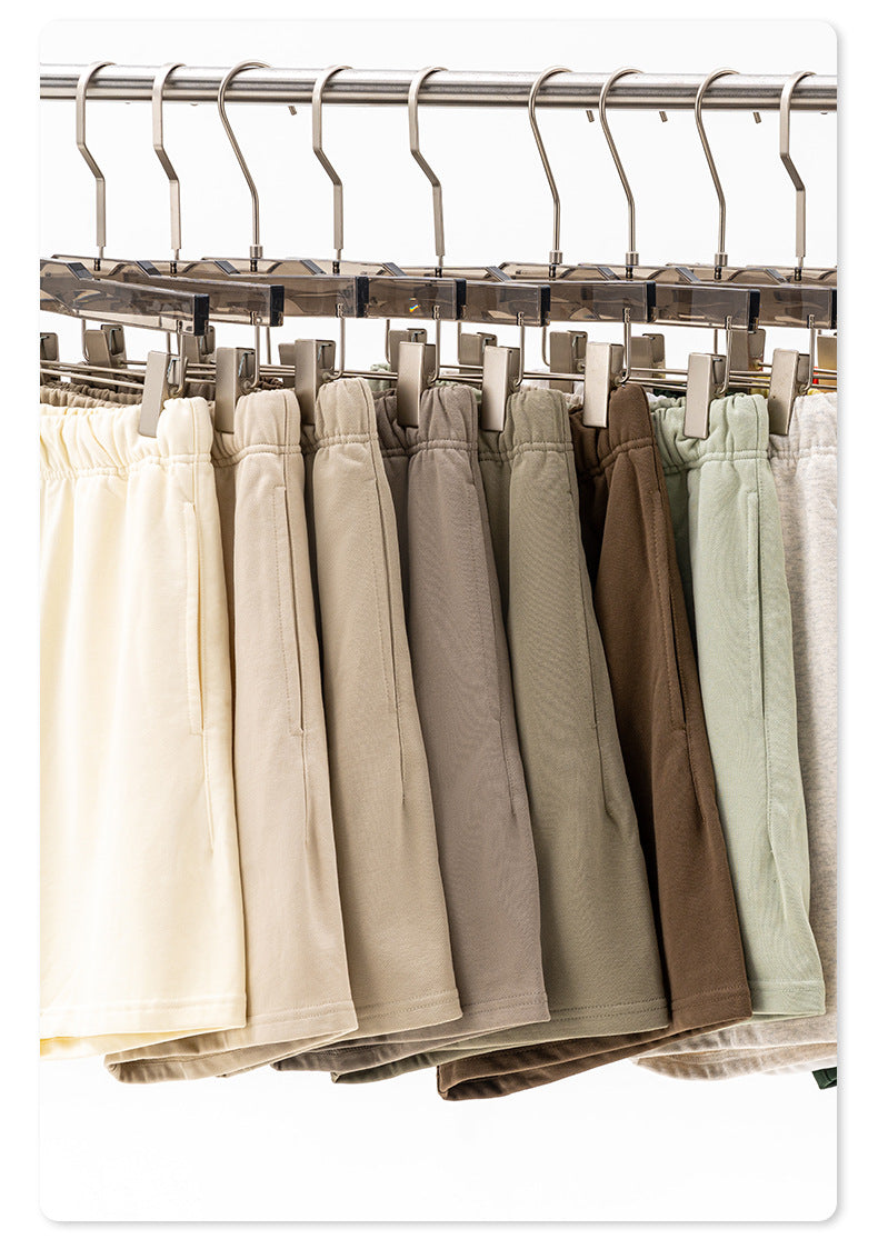 Metal clothing hangers with clips holding various neutral-colored shorts with drawstring waistbands displayed on a rack