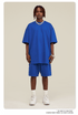 Man wearing royal blue oversized T-shirt and shorts set with white Air Force 1 sneakers and silver chain