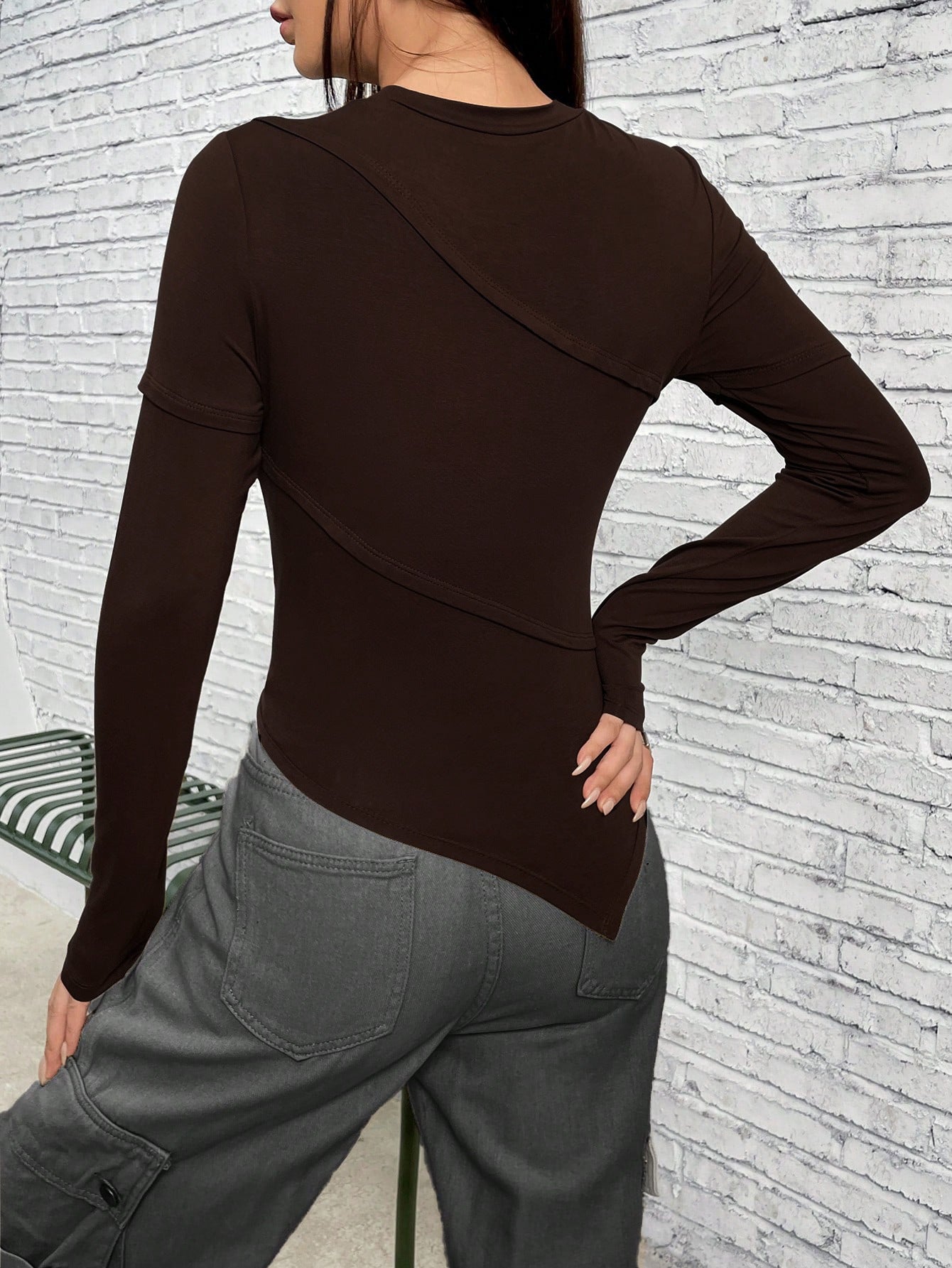 Back view of brown asymmetrical top showing unique seam detailing, paired with gray cargo pants