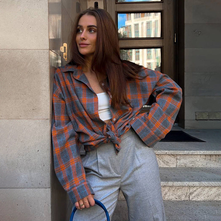 Orange plaid flannel shirt tied with gray pants and white crop top