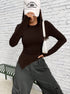 Side angle of outfit featuring brown fitted top, white shoulder bag, and gray cargo pants