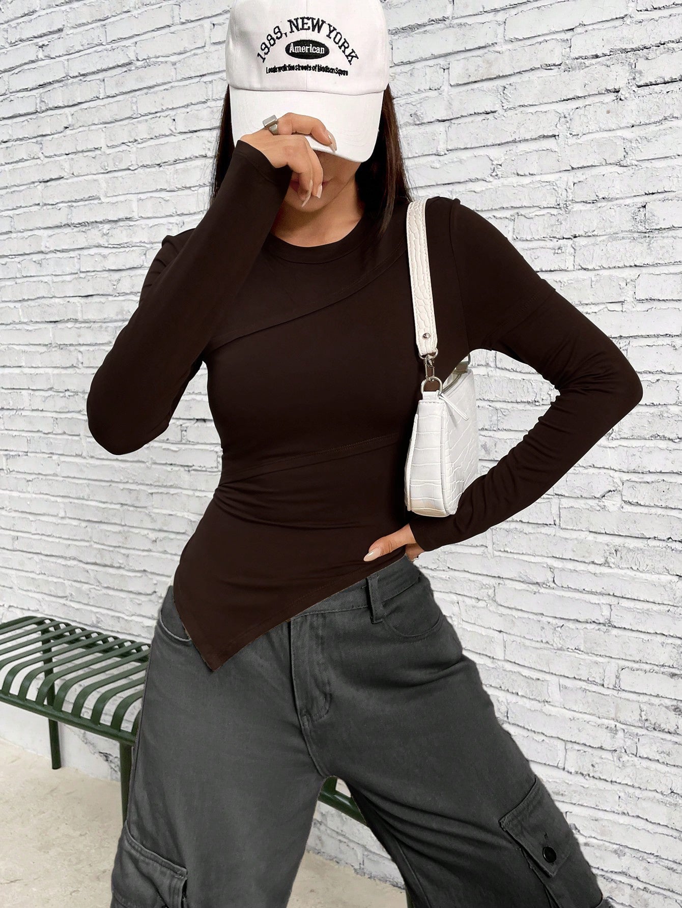 Side angle of outfit featuring brown fitted top, white shoulder bag, and gray cargo pants