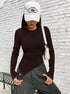 Front view of model in white cap, brown asymmetrical top, and gray cargo pants, looking down