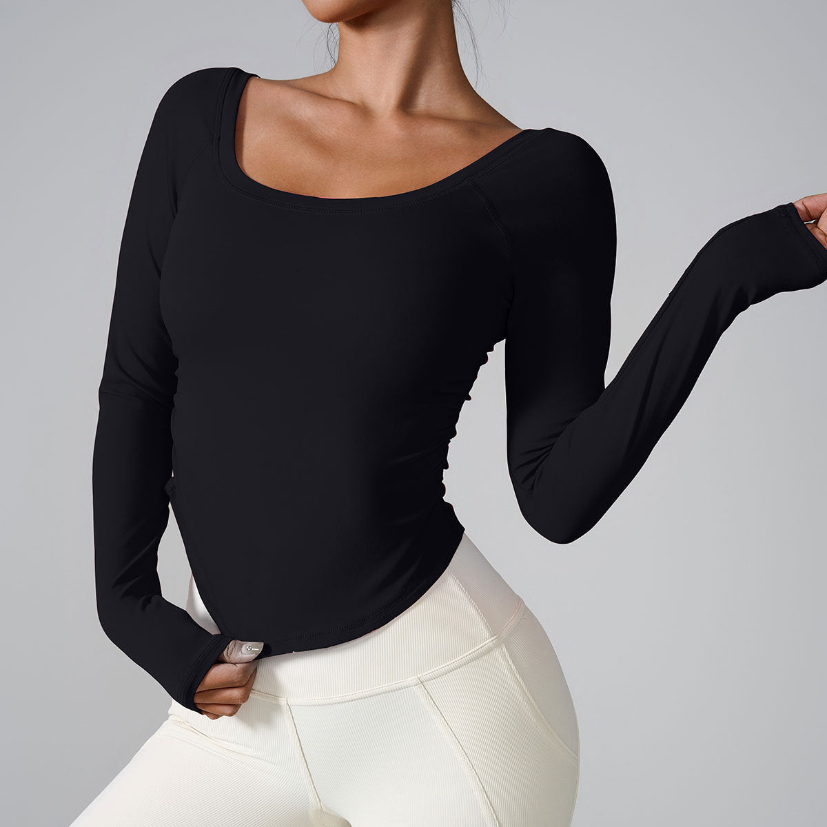 A model wearing a black long-sleeve fitted top with square neckline, paired with cream-colored high-waisted leggings, against gray background