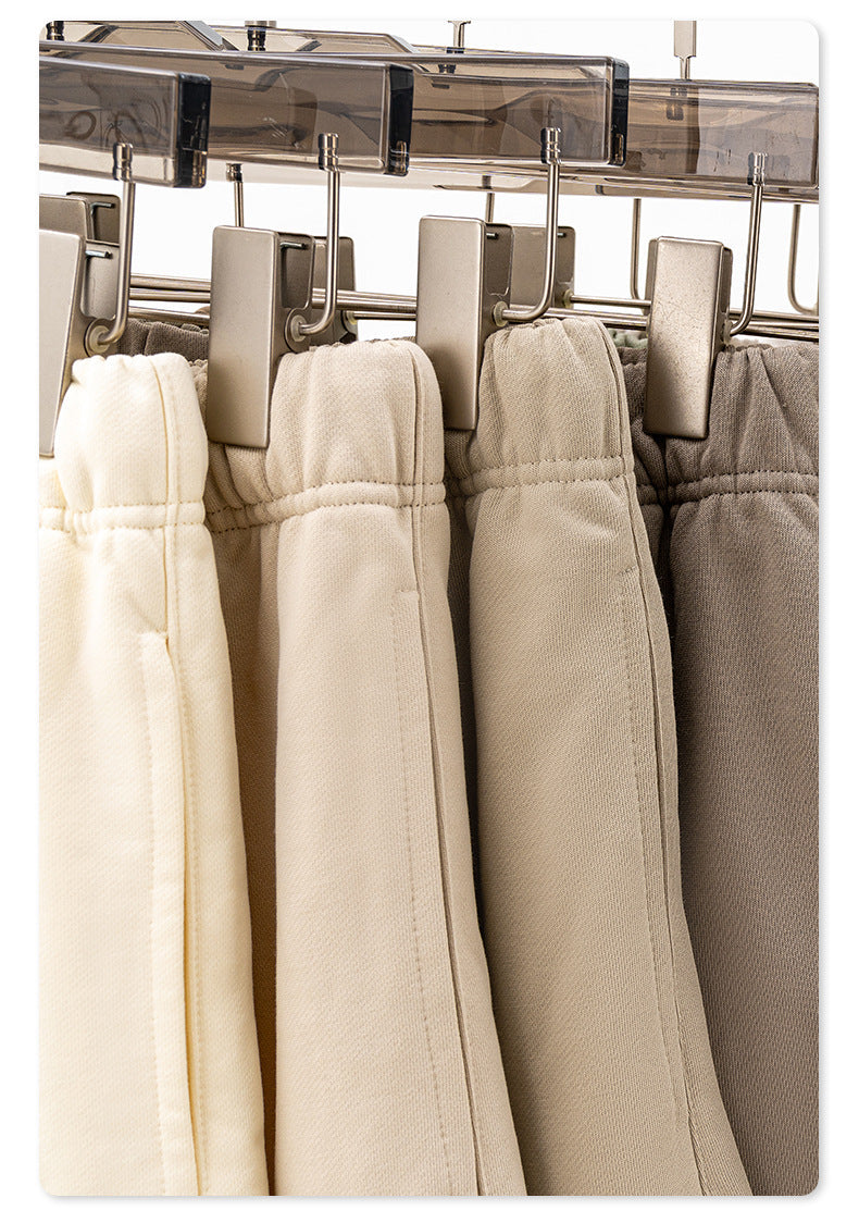 Close-up of metal clothing clips holding various beige and gray shorts with elastic waistbands and drawstrings