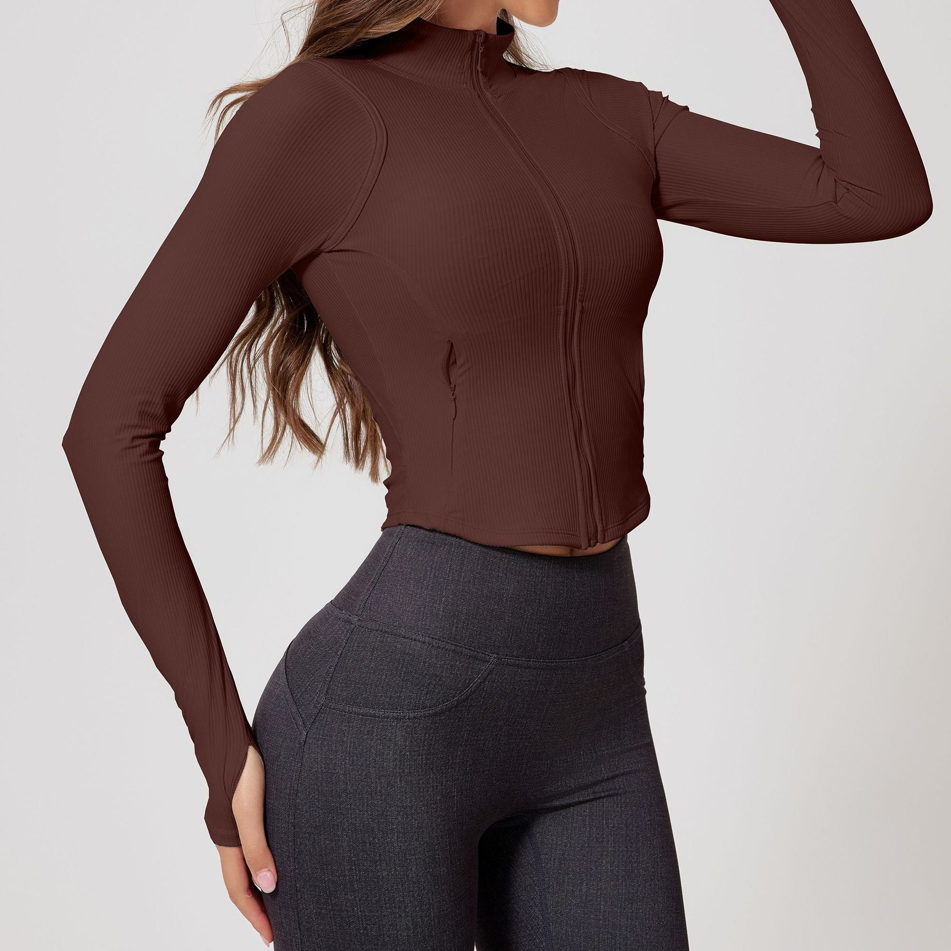 Woman modeling a chocolate brown ribbed zip-up cropped jacket with long sleeves and a fitted design