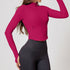 Woman wearing a vibrant pink ribbed zip-up cropped jacket with long sleeves and a sculpted fit