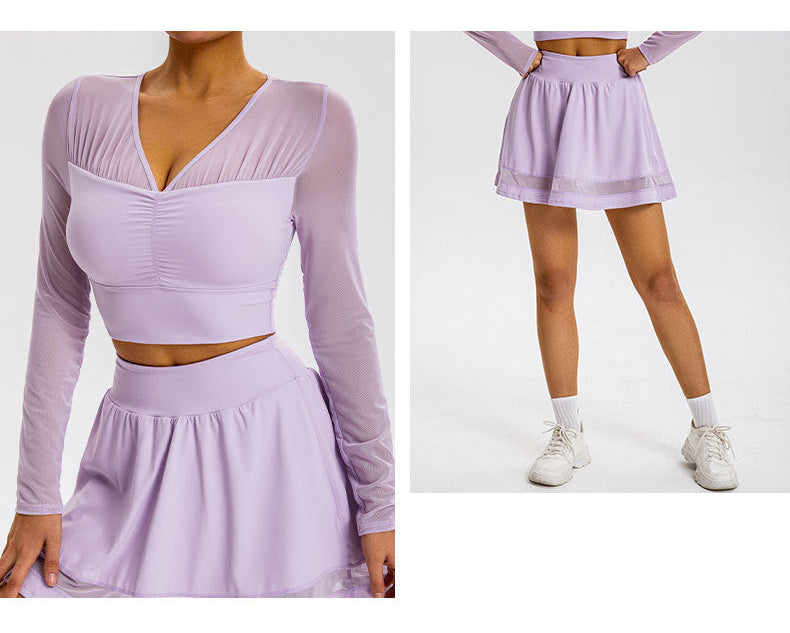 A model is wearing a lavender mesh-sleeve crop top with V-neckline and matching mini skirt, full-length view showing white sneakers against a gray background