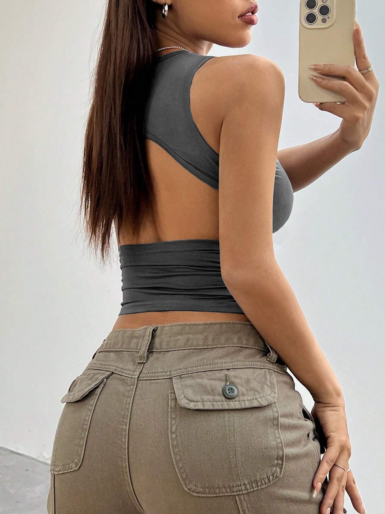 Stylish gray crop top with open-back detail, captured in mirror selfie with smartphone and silver necklace
