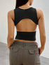 Back view of black crop top revealing distinctive cut-out design, paired with olive cargo pants