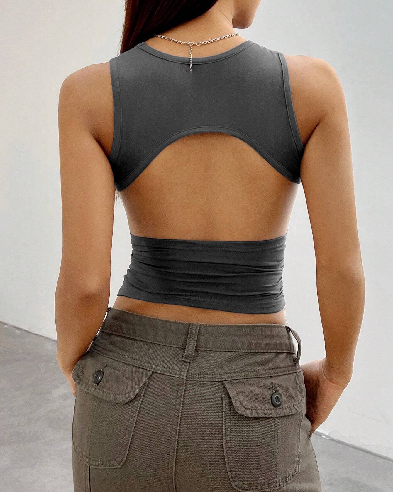 Back view of gray crop top with cut-out design, highlighting trendy open-back silhouette and fitted waistline