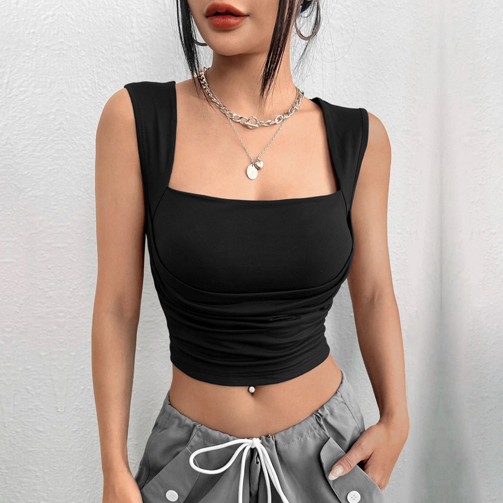 Close-up of black square neck crop top with ruched sides and layered silver necklaces, styled with grey pants