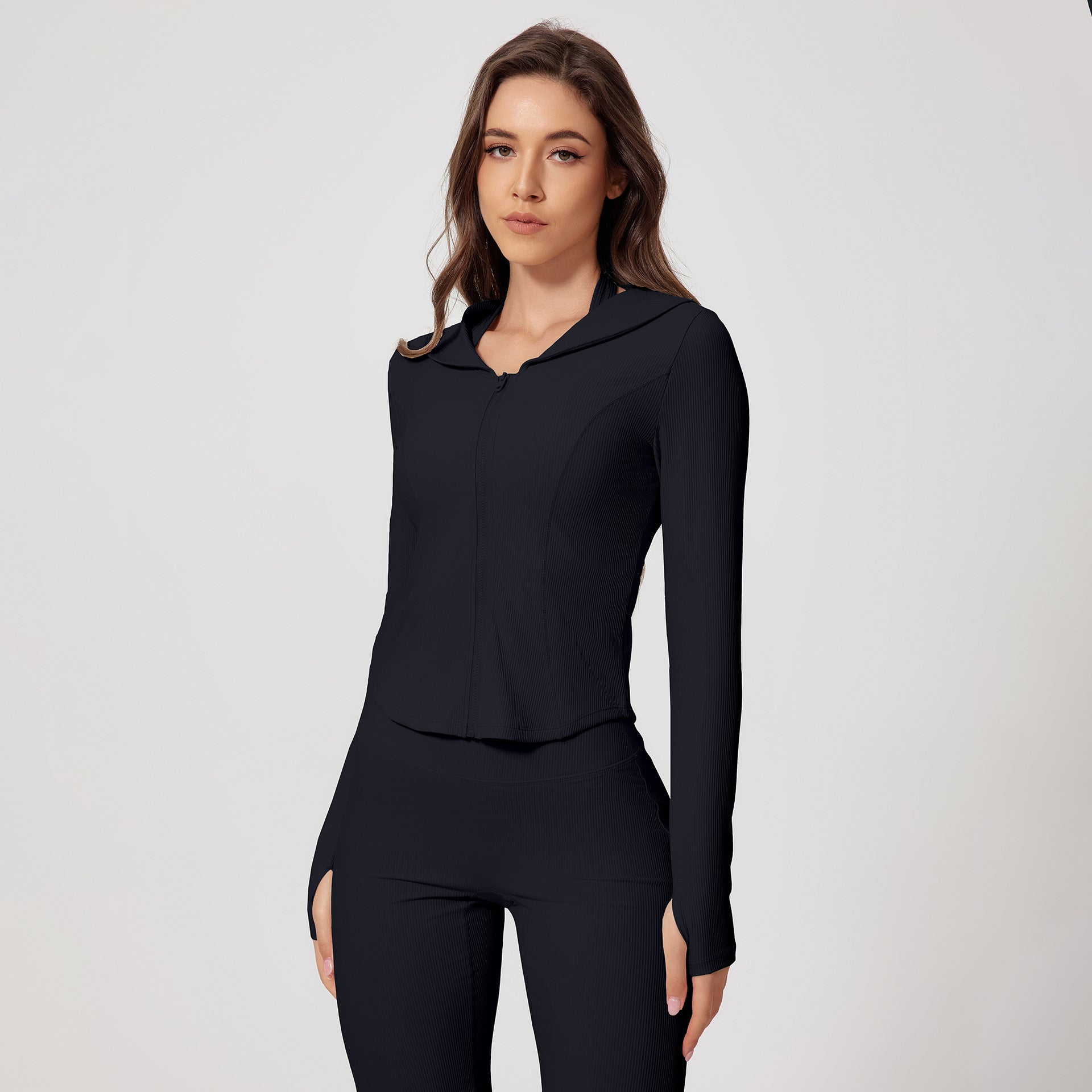 Model wearing a black ribbed workout set featuring a hooded jacket and fitted pants with split hem detail
