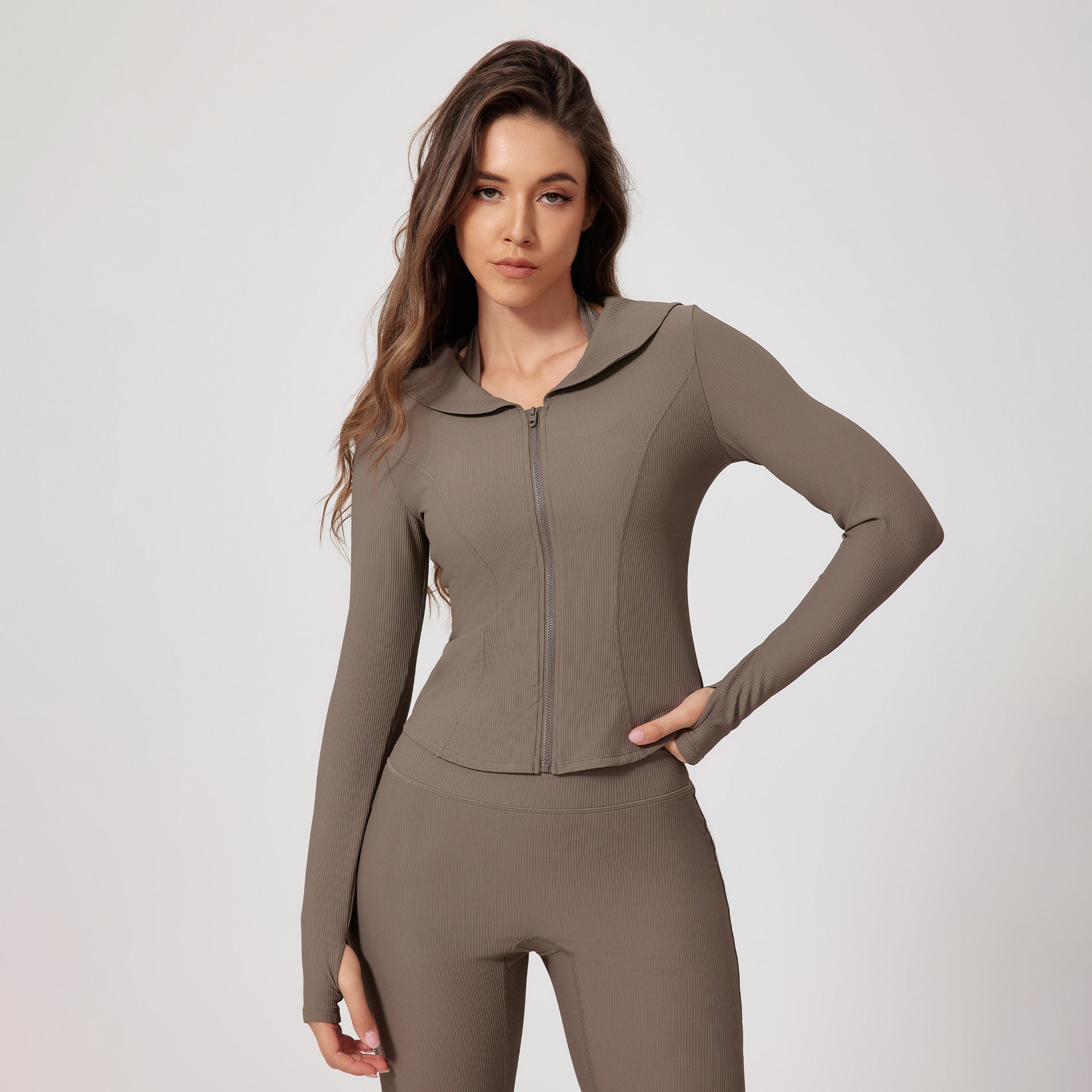 Woman in taupe colored activewear set with zip-front jacket, hooded collar and matching fitted leggings