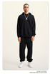 Man with braids wearing black hoodie and pants with silver chain pendant and white sneakers