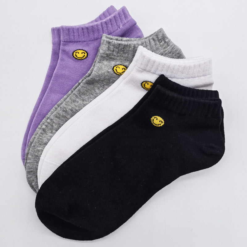 Set of four ankle socks with yellow smiley face design in purple, gray, white, and black