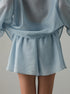 Light blue outfit with a skirt and long sleeves on a neutral background