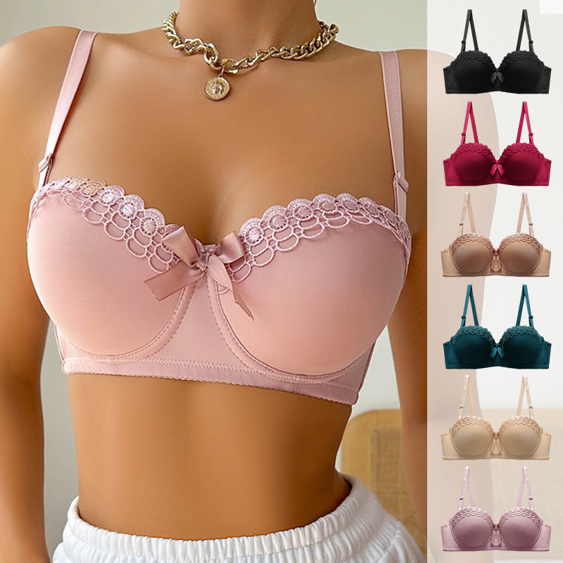 A woman wearing a soft pink push-up bra with lace trim and gold chain necklace, paired with white bottom against light background