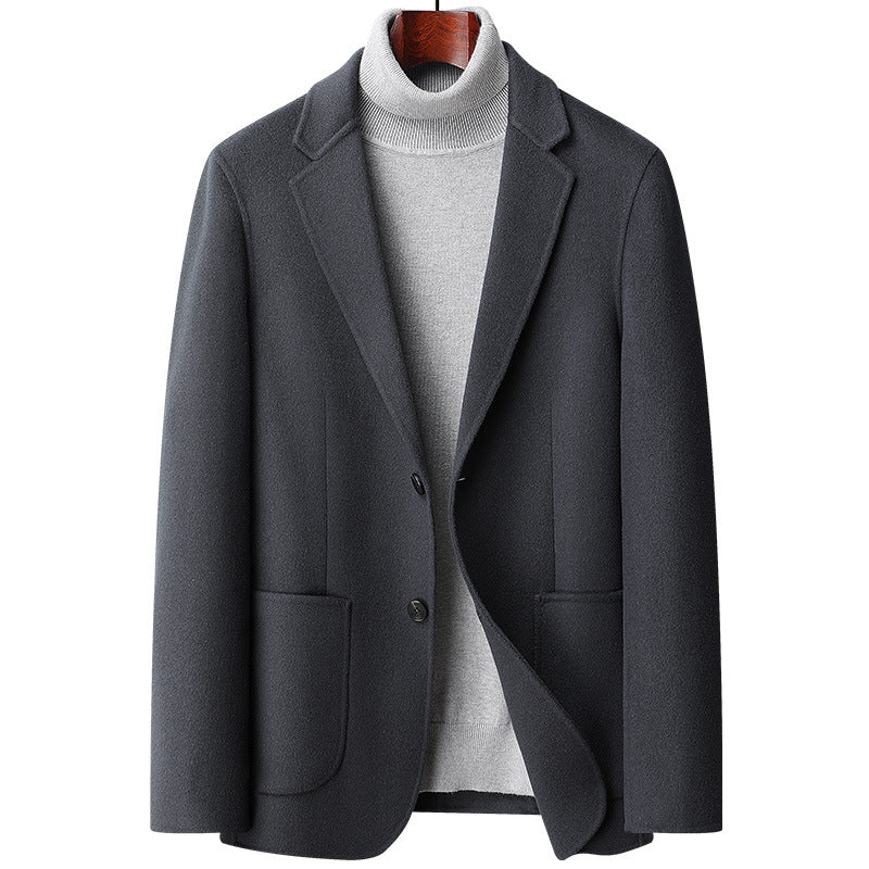 Charcoal gray wool blazer with notched lapels and two-button closure, styled with a light gray turtleneck sweater on wooden hanger