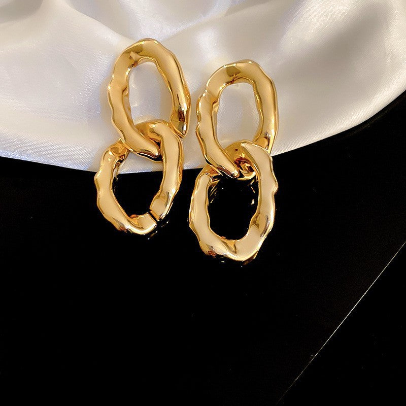 Chunky Gold Link Earrings – Bold gold earrings with an organic, interlocking link design, set against a satin background