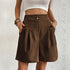 Model wearing Coffee Brown pleated shorts with dual button closure and side pockets, paired with white crop top