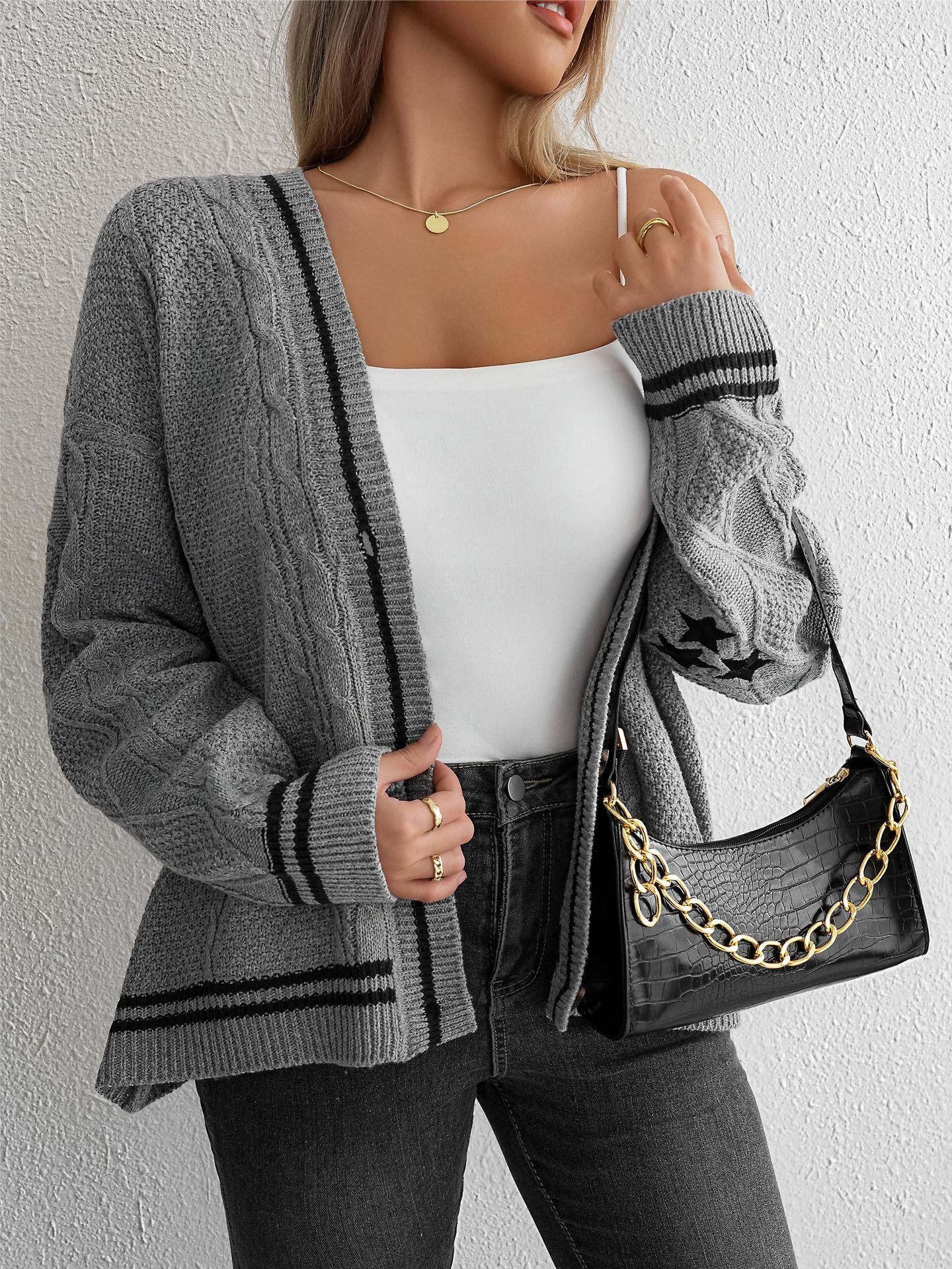 Gray cable knit cardigan with black trim, styled with white top and black leather bag, showcasing versatile layering
