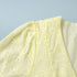 Close-up of a light yellow fabric with floral patterns on a light blue background