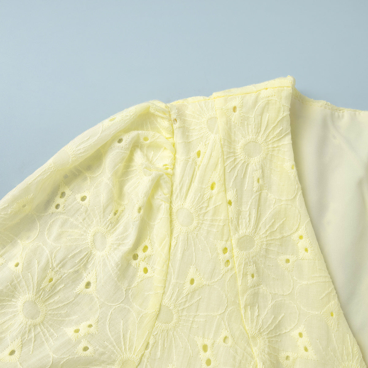 Close-up of a light yellow fabric with floral patterns on a light blue background