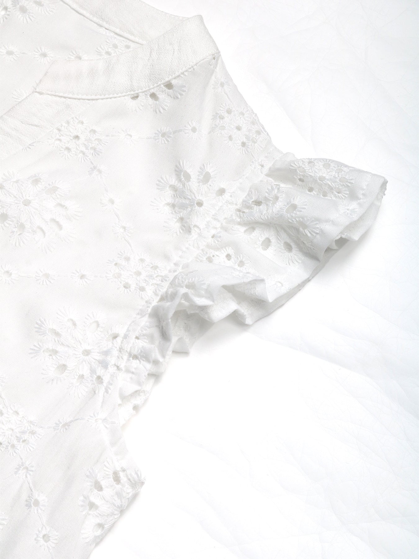 Ruffled sleeve detail of the white lace blouse, showcasing feminine and airy fabric texture.