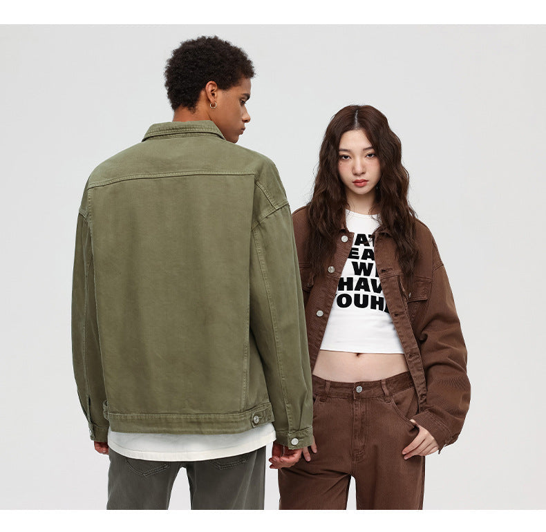 A woman wearing brown denim set and white graphic tee poses beside man shown from behind in olive denim jacket