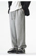 A model is wearing gray sweatpants with a relaxed fit, elastic cuffs, and a small embroidered logo
