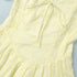 Yellow dress with eyelet details on a light blue background