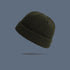 A army green ribbed knit beanie with folded cuff floating against slate gray background, displaying classic winter hat design