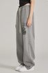 Side view of model in black crop top and oversized grey sweatpants with graphic print. Shown with white Air Force 1 sneakers