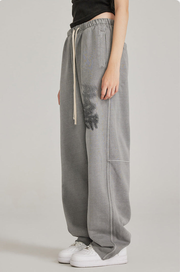 Side view of model in black crop top and oversized grey sweatpants with graphic print. Shown with white Air Force 1 sneakers