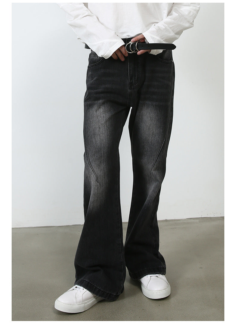 A model adjusting black leather belt with silver buckle, wearing black wide-leg jeans and white sneakers against minimalist backdrop