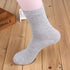 Gray cotton crew sock positioned on white mannequin leg with wooden surface