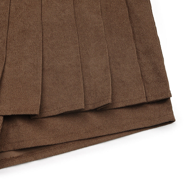Zoomed-in detail of the pleated layers of the brown mini skort, showing the fabric thickness.