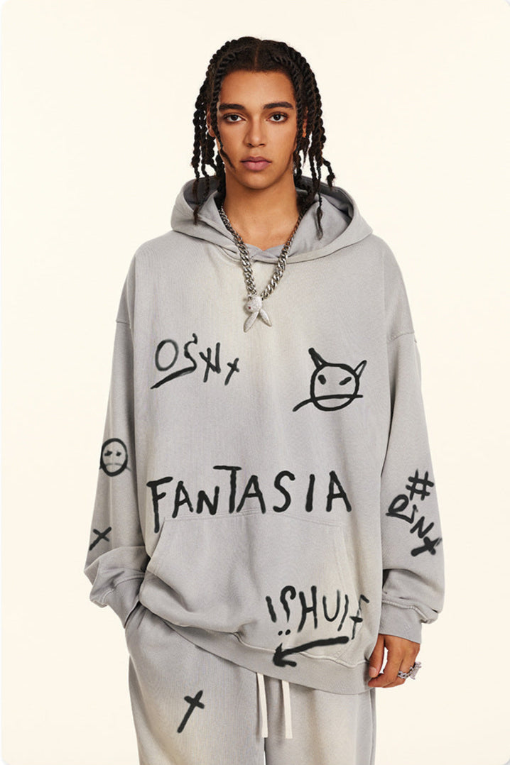 Model with twisted braids wearing light gray hoodie with graffiti-style graphics featuring 'FANTASIA' text and devil emoji designs