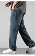 A person walking in loose-fitting medium wash straight leg jeans with gray t-shirt and silver bracelet, paired with classic white Nike Air Force 1 sneakers