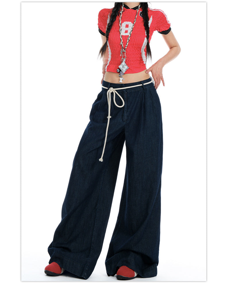 Cropped shot of model wearing dark wide-leg jeans, emphasizing rope-tied waist and relaxed fit.