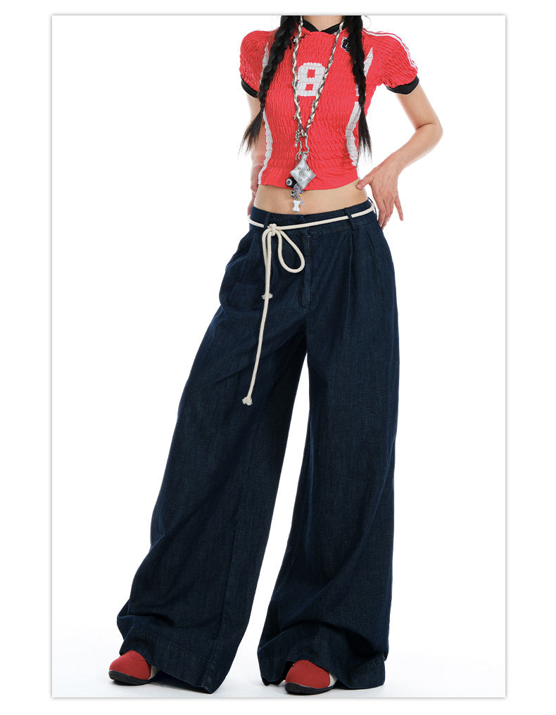 Cropped shot of model wearing dark wide-leg jeans, emphasizing rope-tied waist and relaxed fit.